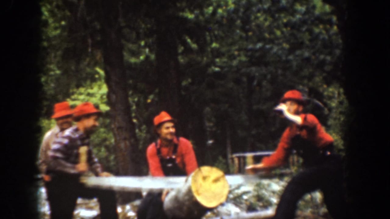 Chelan, Washington 1939 frame of several men around a large log and crosscut saw, with one man gesturing while holding a bottle.
