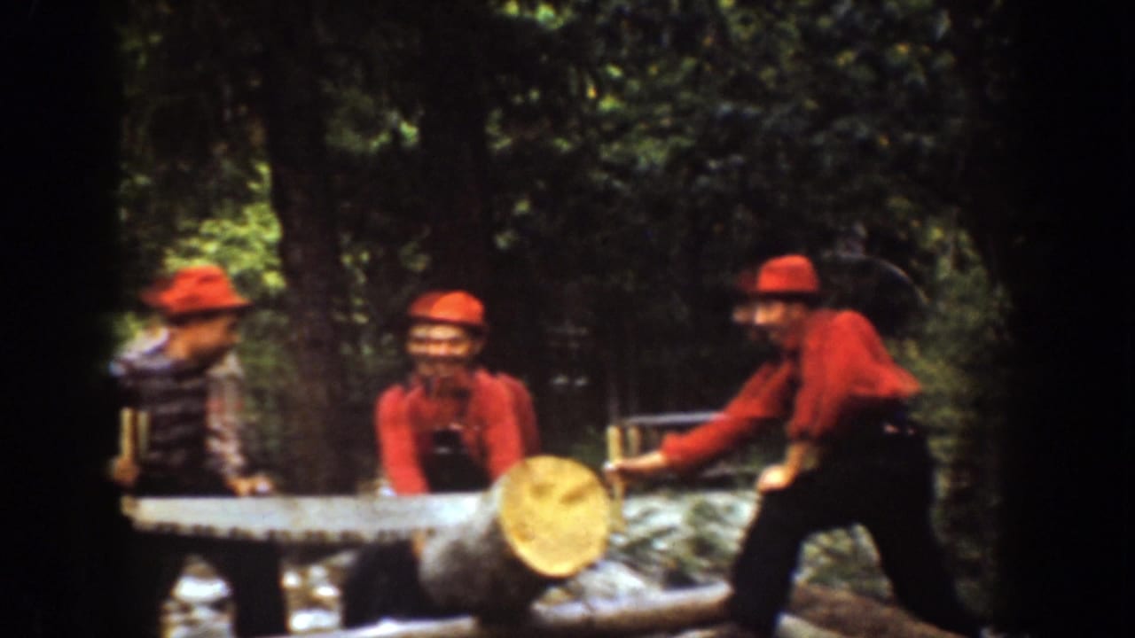 Men in red hats and work clothes appear to smile and pause near a large log and crosscut saw in 1939 Chelan, Washington footage.