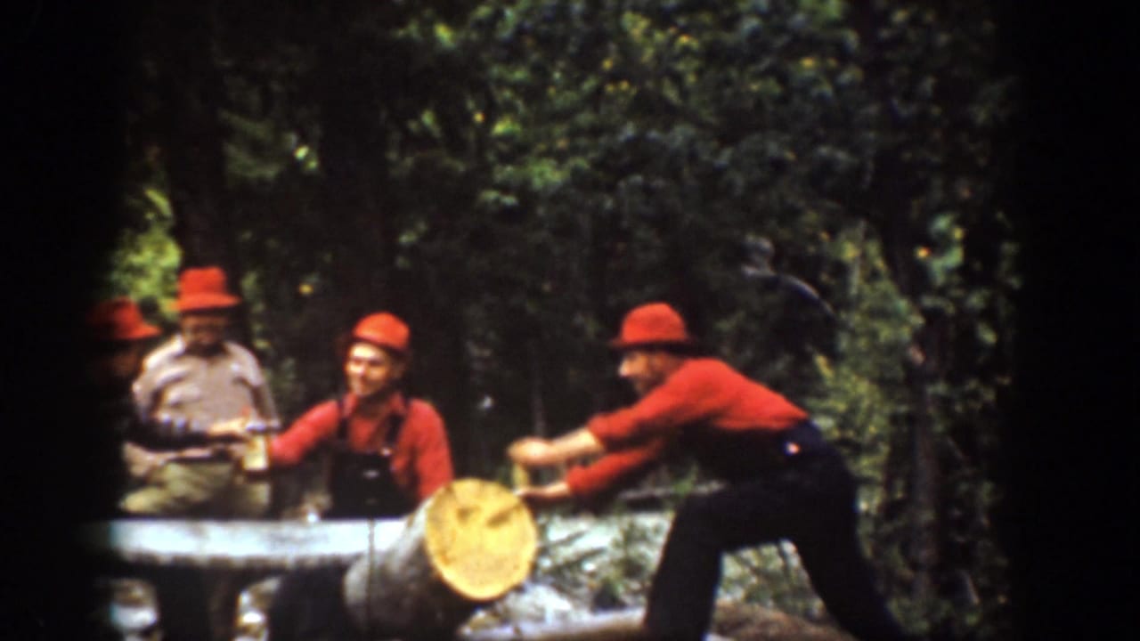 Chelan, Washington 1939 frame showing a worker in red shirt and dark overalls pushing a log as other men stand nearby.