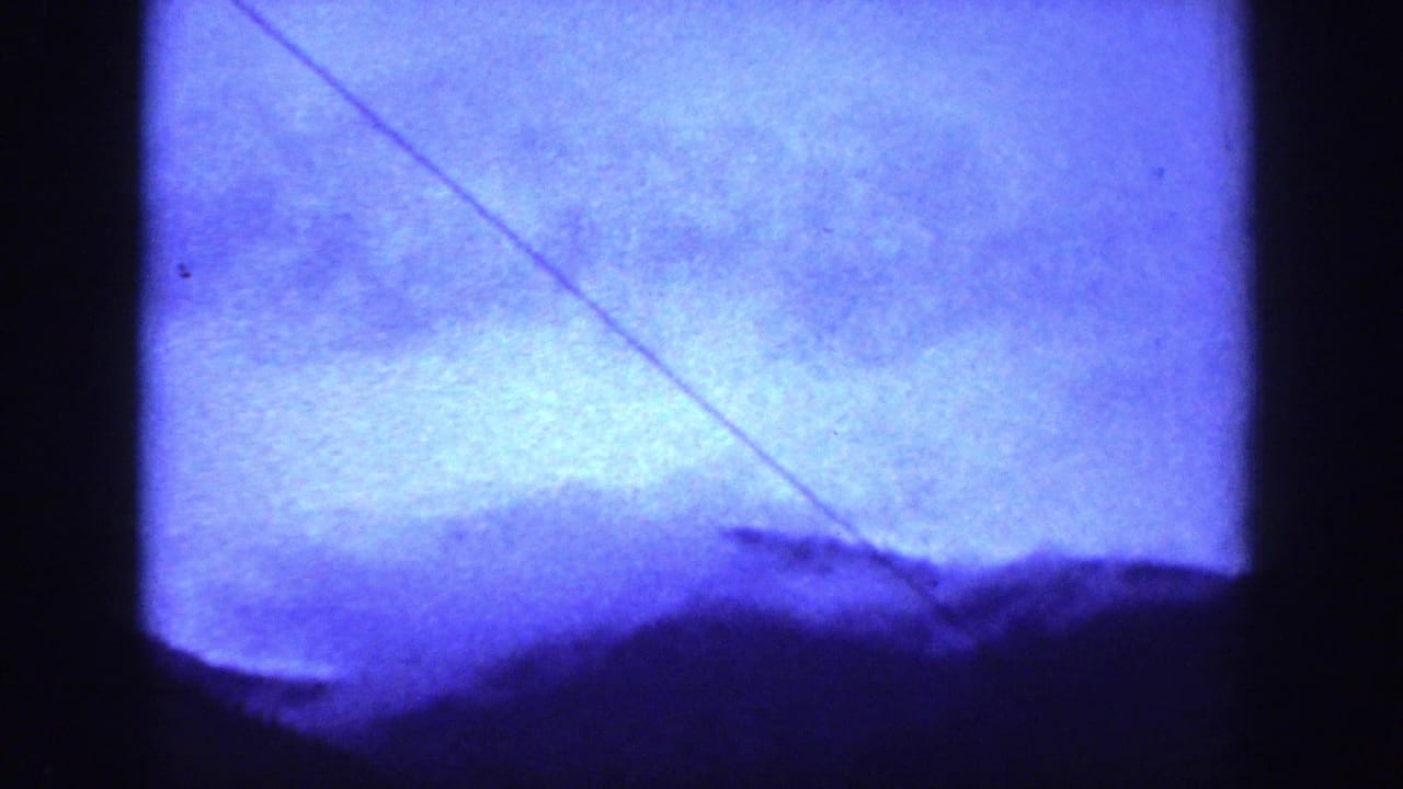 Blue-toned 1939 home-movie landscape frame showing distant mountain forms, a dark ridge, and a diagonal line across the sky.