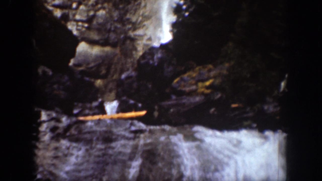 Chelan, Washington waterfall detail with rushing water, dark rocks, and a narrow horizontal wooden element in frame.