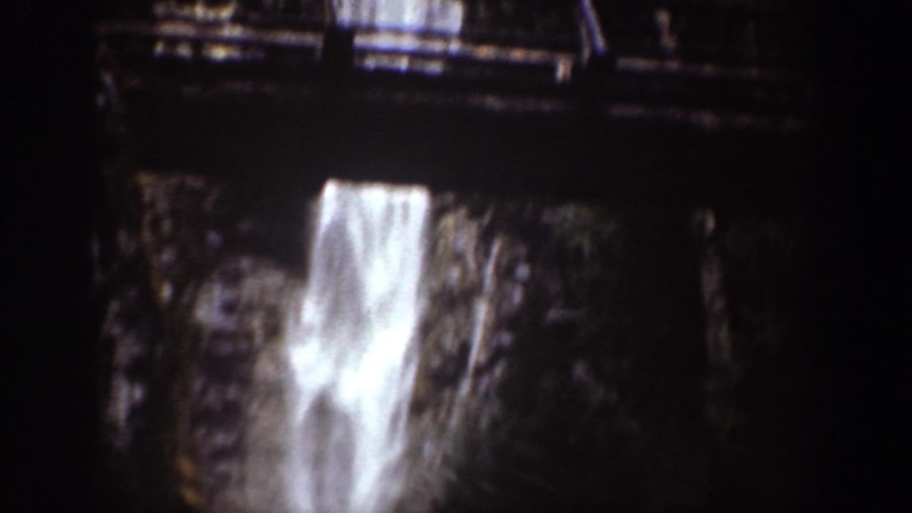 Close 8mm view of a bright waterfall plunging between dark rocks in Chelan, Washington.