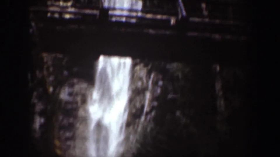 Close 8mm view of a bright waterfall plunging between dark rocks in Chelan, Washington.