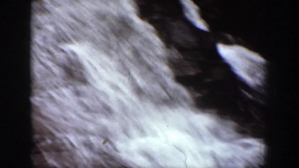 1939 8mm frame showing a diagonal sheet of white cascade water beside dark rock in Chelan, Washington.