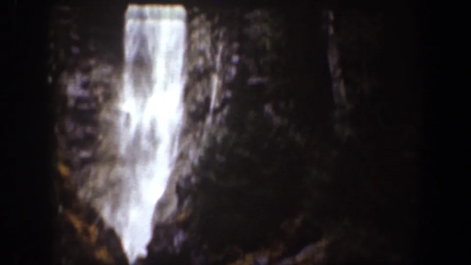 1939 Chelan, Washington home-movie frame showing a bright waterfall dropping between dark rocks and trees.