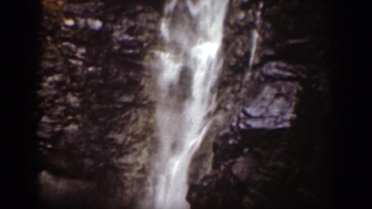 1939 Chelan, Washington frame showing a closer view of the waterfall descending through rocks and trees.
