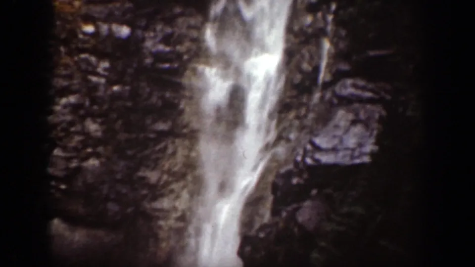 1939 Chelan, Washington frame showing a closer view of the waterfall descending through rocks and trees.