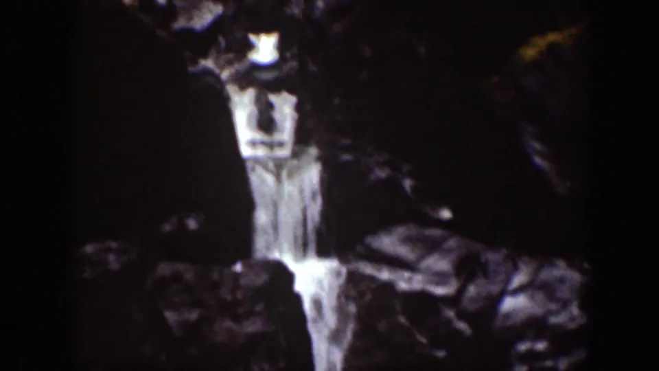 1939 Chelan, Washington 8mm frame showing a narrow waterfall descending between dark, shadowed rocks.