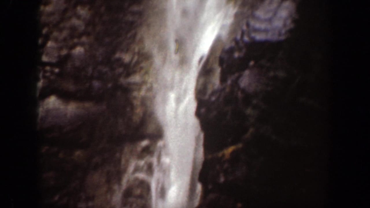 Close 8mm view of the waterfall in Chelan, Washington, with bright water against dark rock texture.