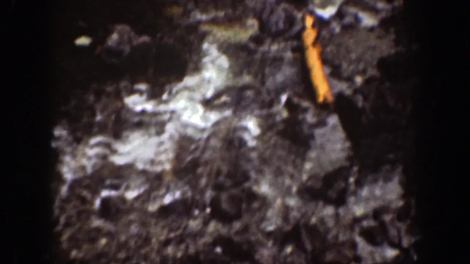 Foamy water moves across dark rocks in the Chelan waterfall footage, with a visible orange film artifact along the right edge.