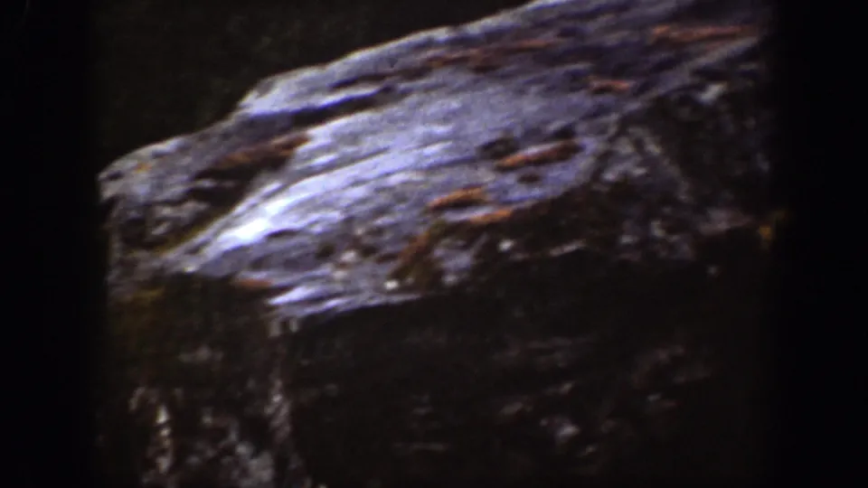 1939 8mm Chelan footage showing a dim room with a rough foreground surface and heavy shadow obscuring most details.