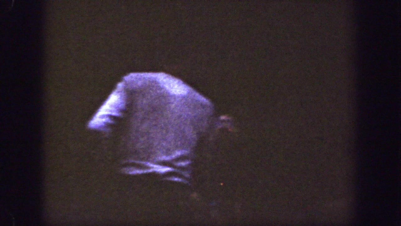 A person in a light-colored shirt stands or turns away in the dim Chelan, Washington gathering footage.