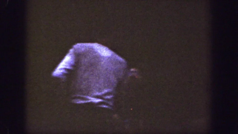 A person in a light-colored shirt stands or turns away in the dim Chelan, Washington gathering footage.
