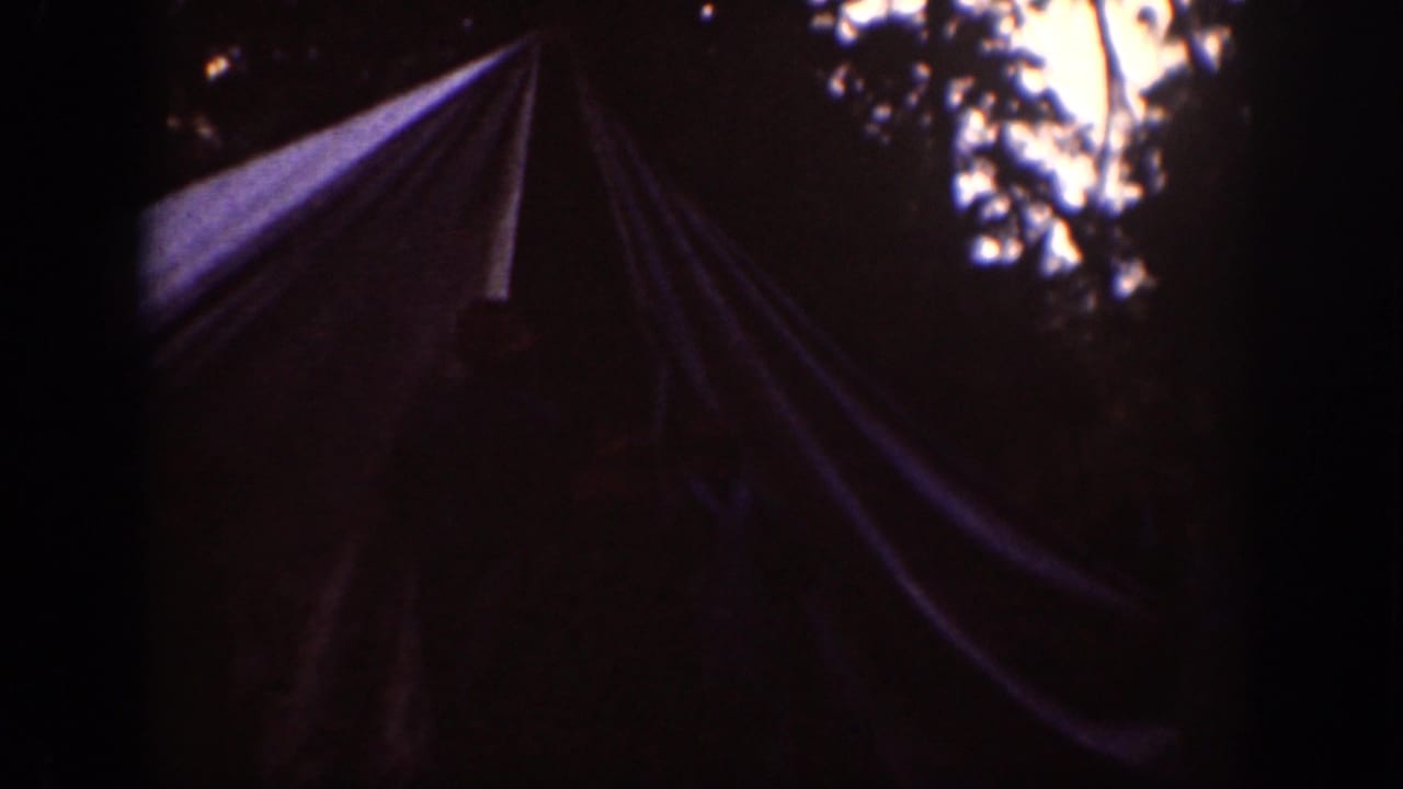 1939 Chelan, Washington home-movie frame showing a canvas tent in a shaded wooded campsite with dark film edges.