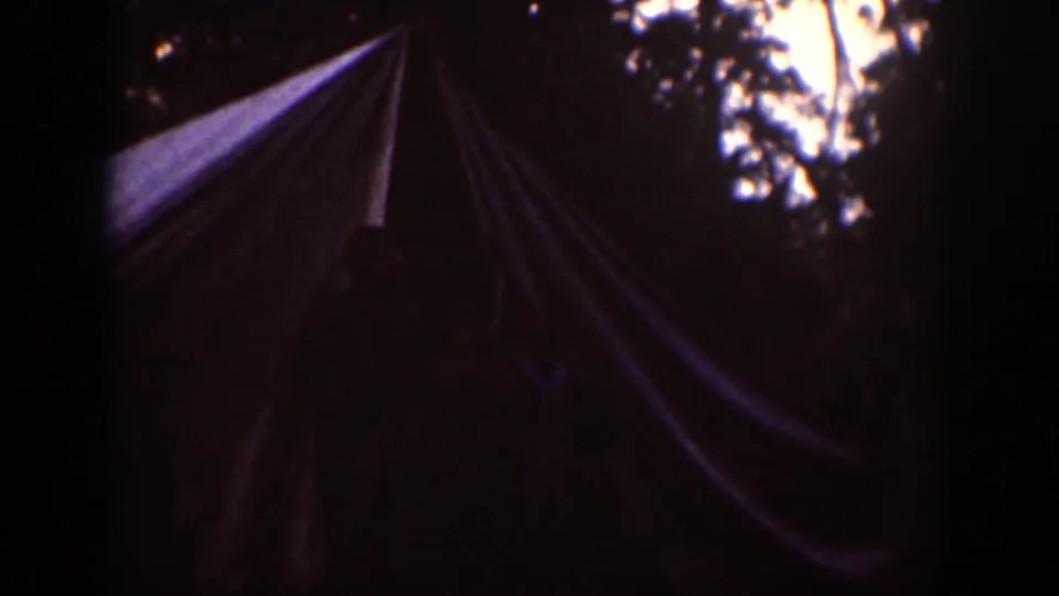 1939 Chelan, Washington home-movie frame showing a canvas tent in a shaded wooded campsite with dark film edges.