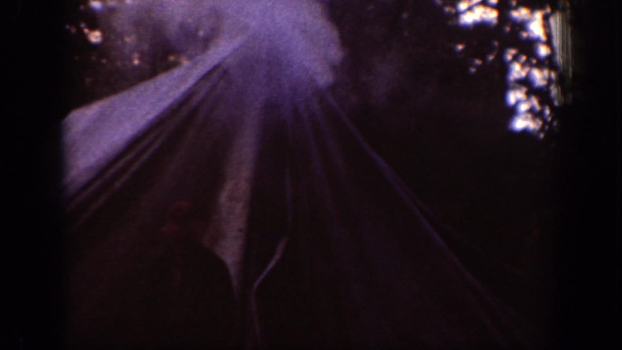 1939 Chelan, Washington frame of a tent in the woods, with bright smoke or overexposed light above the canvas.