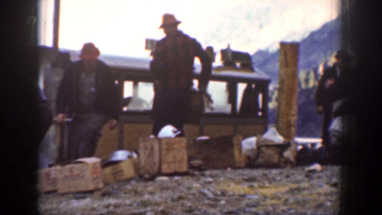 Men in hats stand around wooden crates and parcels beside a small carriage in 1939 Chelan, Washington footage.