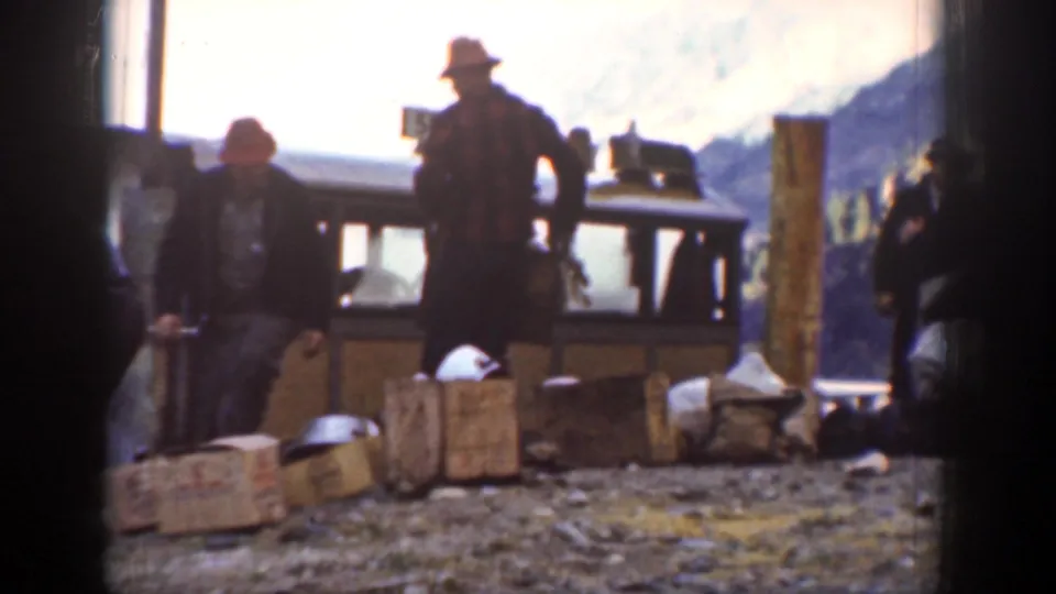 Men in hats stand around wooden crates and parcels beside a small carriage in 1939 Chelan, Washington footage.