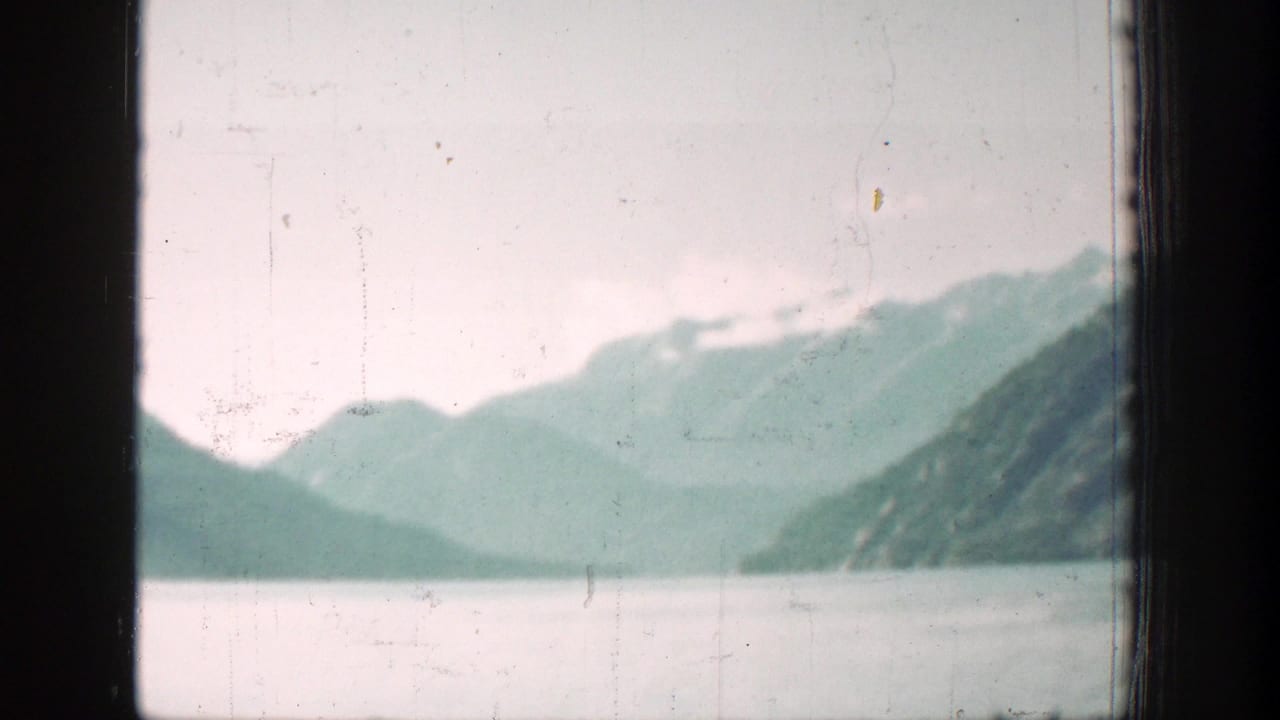 1939 Chelan, Washington home-movie view of a broad lake and hazy mountains through a dark window frame.