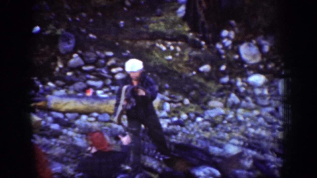 In Chelan, Washington 1939 footage, men appear on a stony forest slope while a white-capped worker bends near a large log.
