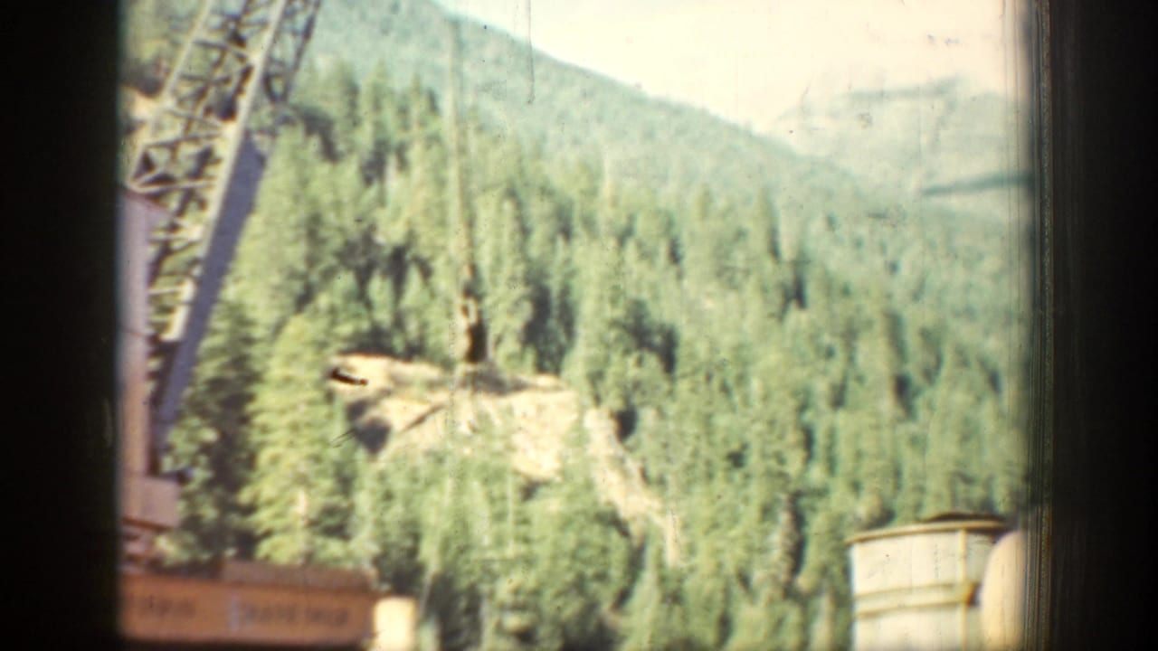 The final 1939 Chelan frame looks across forested hills, with part of a structure or worksite edge visible in the foreground.