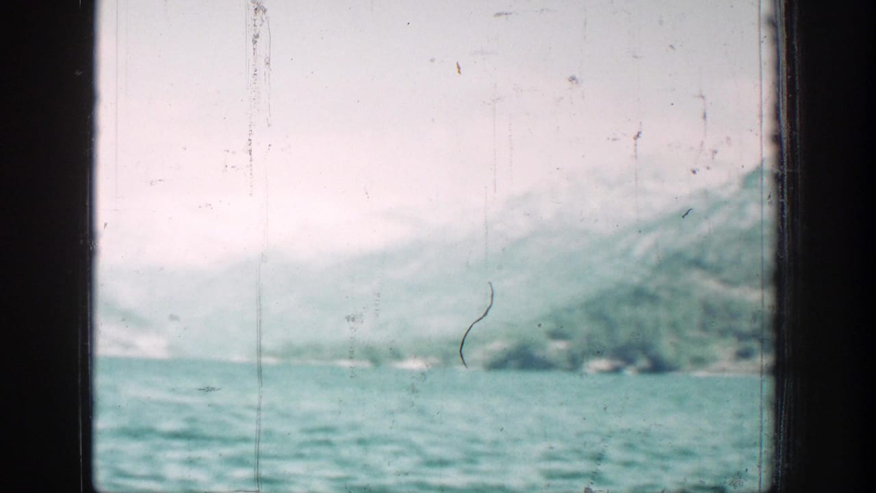 Soft 8mm view of turquoise lake water and pale, snow-dusted mountain slopes near Chelan, Washington.