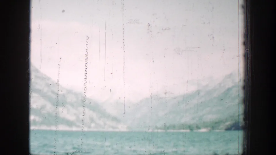 Chelan, Washington mountain lake view on 1939 8mm film, with distant slopes, pale sky, and visible film scratches.