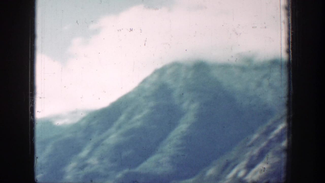 Soft mountain slope seen across a lake through dark film frame borders.