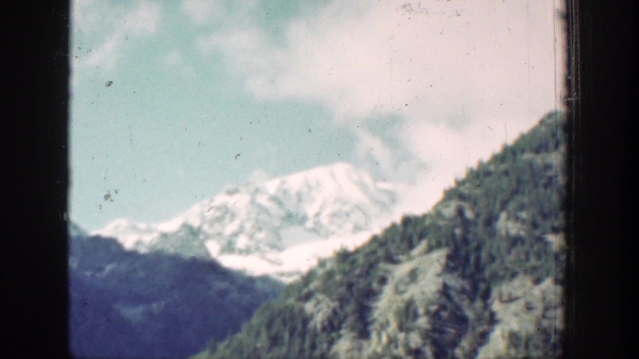 Chelan, Washington mountain view with a snowy peak, wooded slope, pale sky, and visible 8mm film wear.