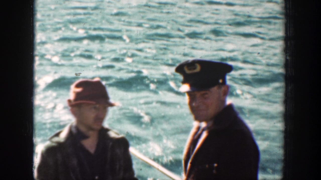 On a Chelan boat in 1939, a red-capped civilian stands near a uniformed man, with rippled lake water in the background.