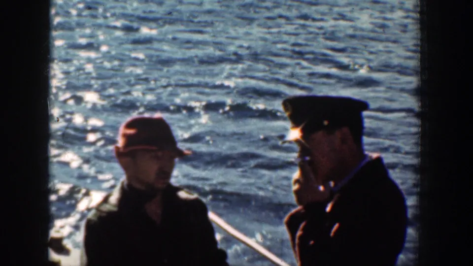 1939 Chelan, Washington home-movie frame showing two men conversing near a boat rail with bright water behind them.