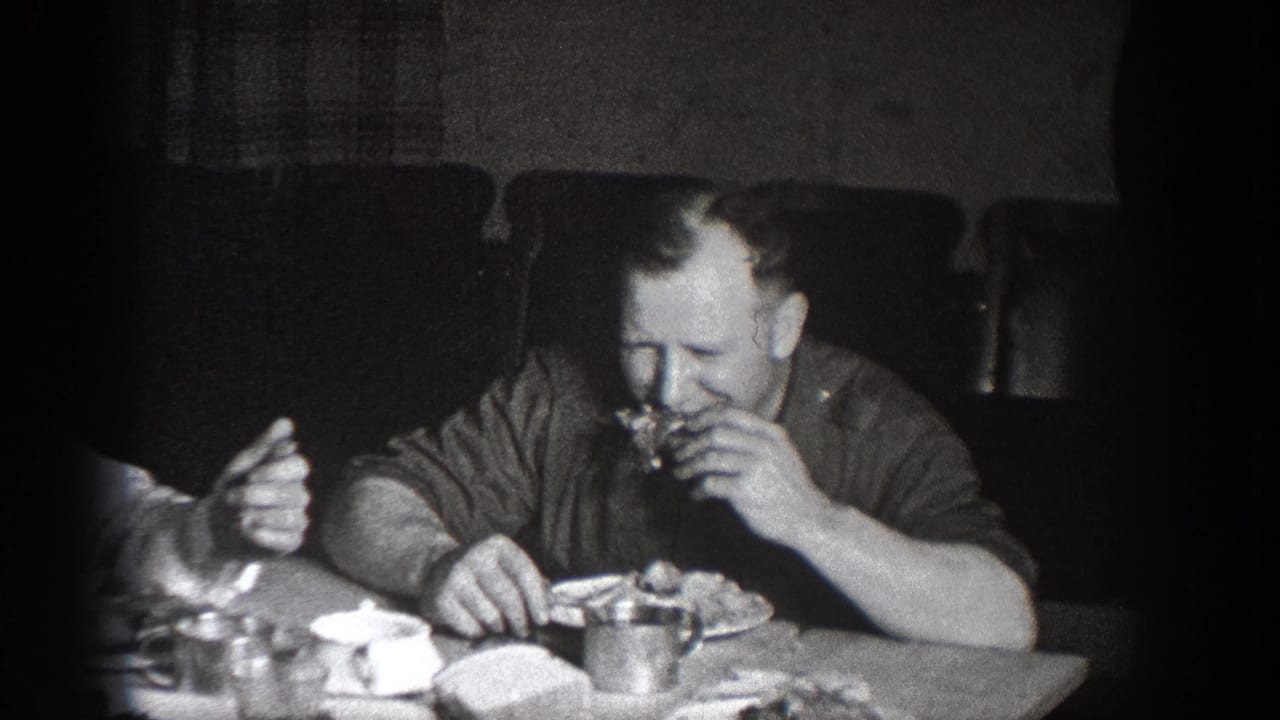1939 Chelan, Washington home-movie frame showing a man in a dark shirt eating at a lunch table in a dim interior.