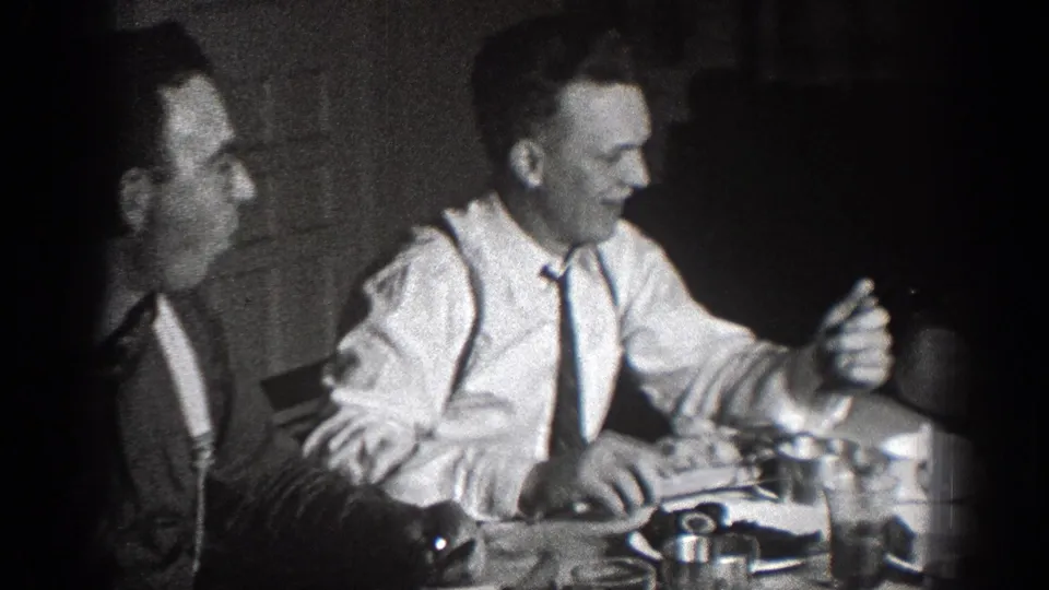 In a 1939 Chelan, Washington home-movie frame, two men in formal shirts and ties sit at a table during a meal.
