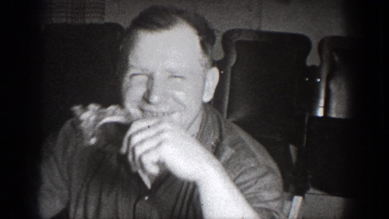 A man smiles while eating in a black-and-white 8mm frame from the 1939 Chelan, Washington gathering.