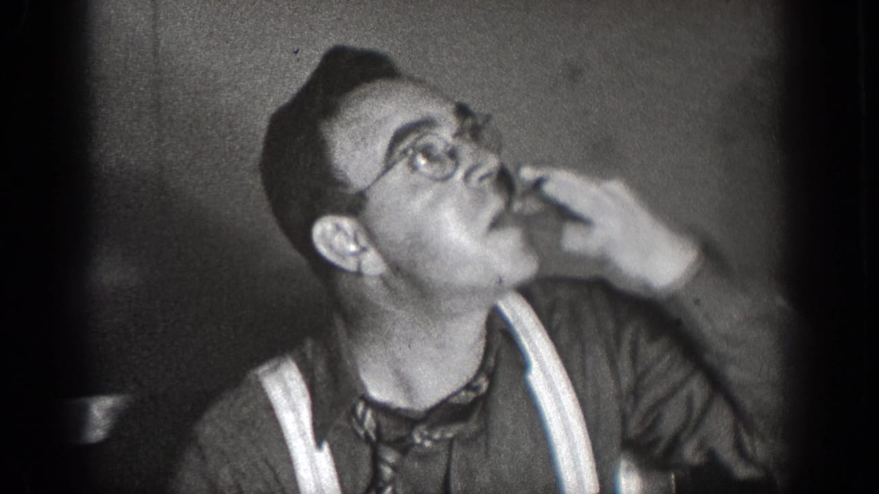 In 1939 Chelan, Washington home-movie footage, a man in glasses and suspenders raises food to his mouth at an indoor meal.