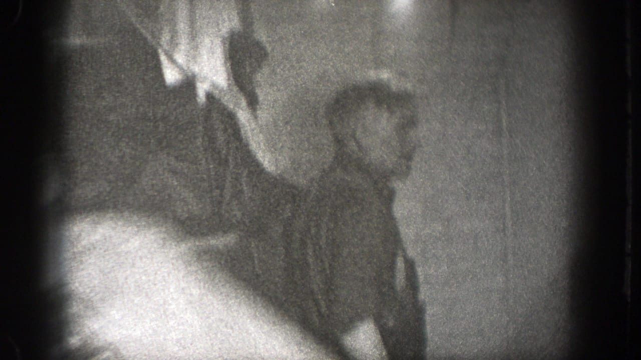 A soft-focus frame shows a seated man near a cup during the indoor meal, with the 8mm image blurred by motion and exposure.