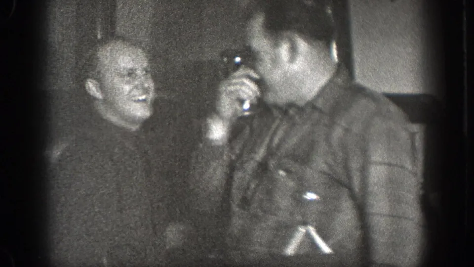 Two adult men appear to share a light moment inside the 1939 Chelan kitchen, with one holding a small cup or vessel near his face.