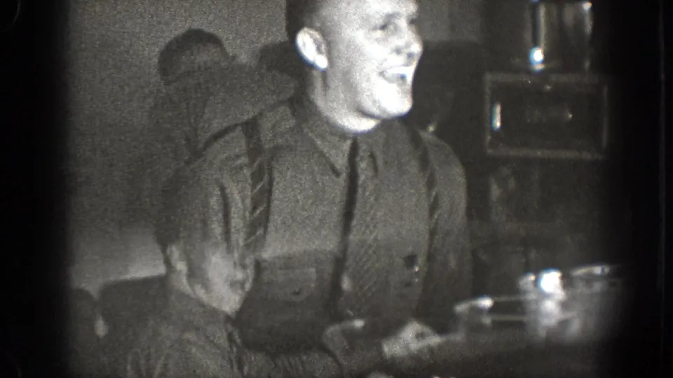 In 1939 Chelan, Washington home-movie footage, a man sits at a table in a dim room and gestures during a meal.