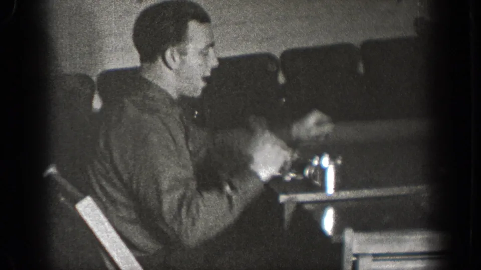 A man in profile sits at a table with cups and dishes in a private interior in Chelan, Washington footage from 1939.