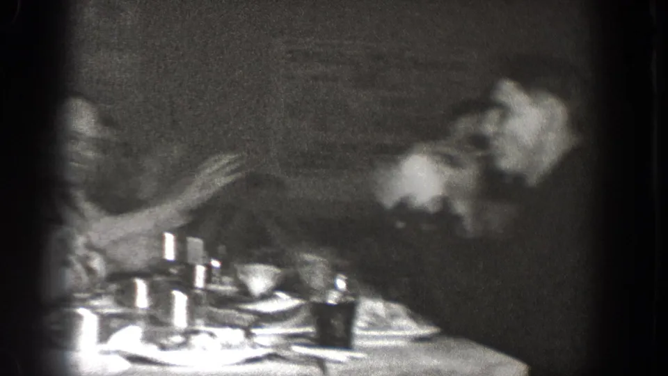Motion blur obscures part of the 1939 Chelan dinner frame, but a seated man and table setting remain visible.