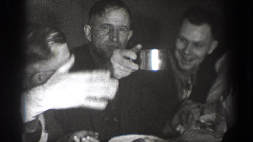 In the final frame, men sit around the Chelan table with plates and cups, including one man holding a metal cup toward the camera side.