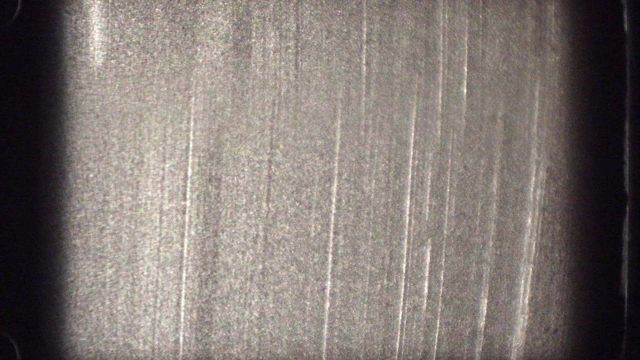 The final frame shows an overexposed 8mm film surface with scratches, grain, and dark rounded frame edges rather than clear figures.