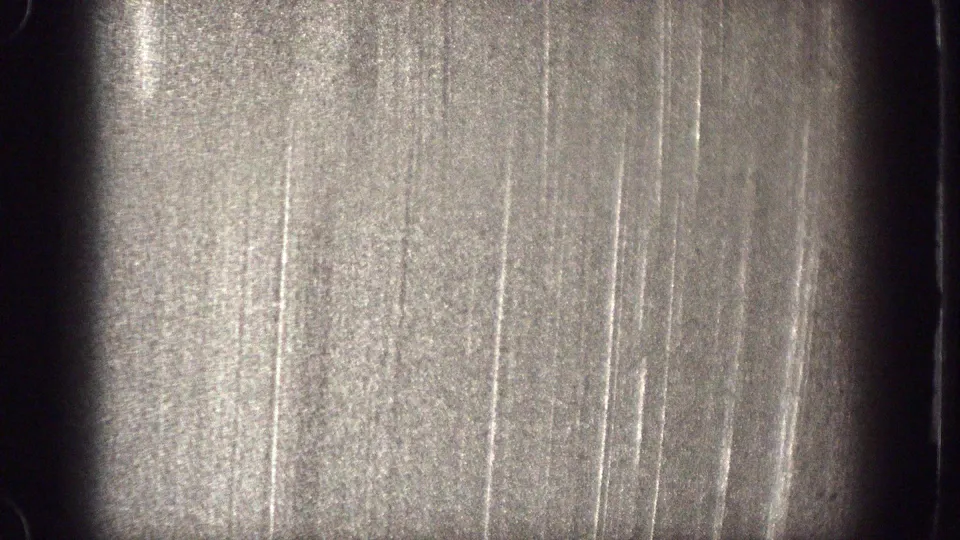 The final frame shows an overexposed 8mm film surface with scratches, grain, and dark rounded frame edges rather than clear figures.