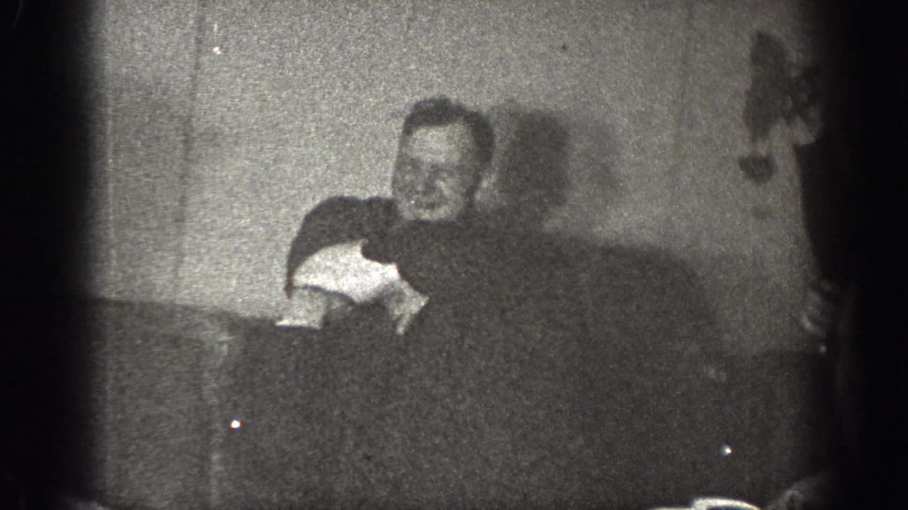 The final frame shows a man leaning forward in the dim Chelan interior, with another figure partly obscured at the edge of the scene.