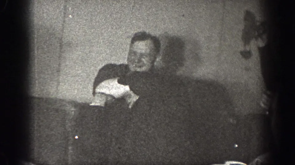 The final frame shows a man leaning forward in the dim Chelan interior, with another figure partly obscured at the edge of the scene.