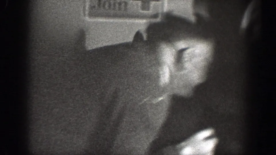 A soft, close 1939 Chelan home-movie frame shows an adult man in a dark jacket seated in a dim private interior.