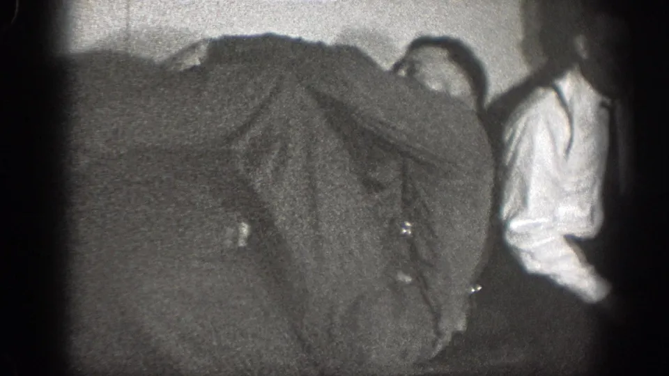 1939 Chelan home-movie frame showing a man bent forward near another figure, with a standing man in a white shirt at the side.