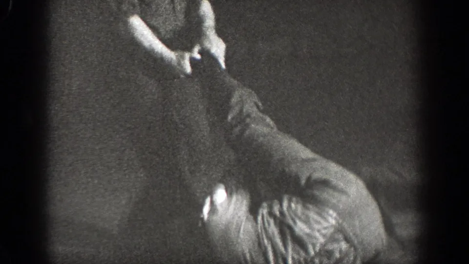 Chelan, Washington 1939 frame showing one adult leaning over a partner during floor-based judo practice.