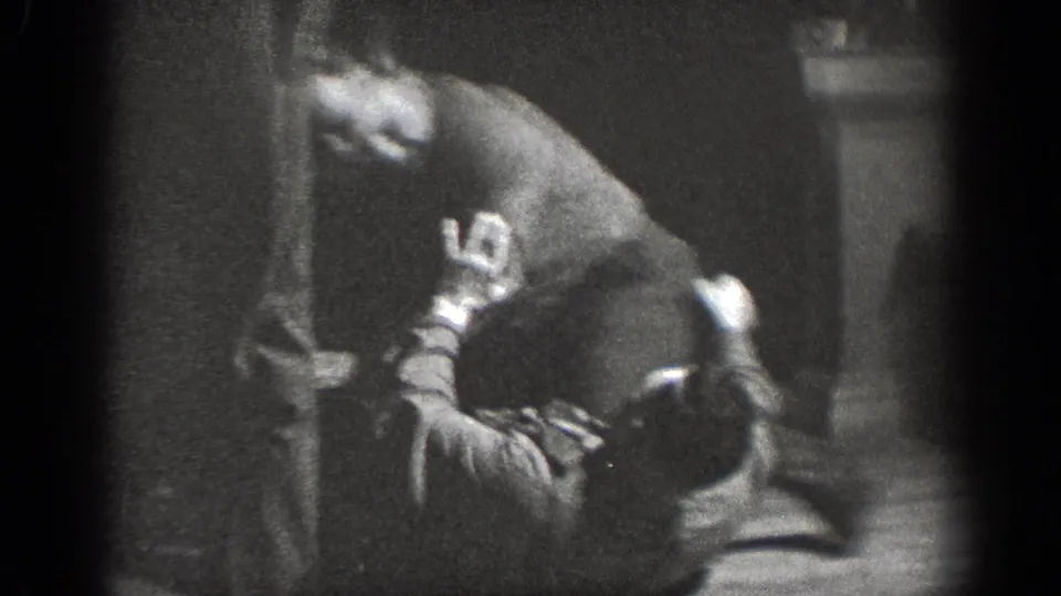 A man in casual clothes bends over another man on the floor while a third adult stands nearby in the Chelan interior.