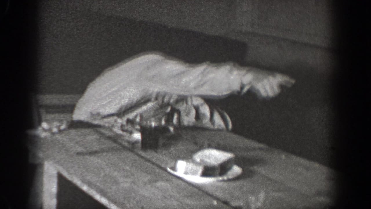 Seated man extends his arm and points across a table.